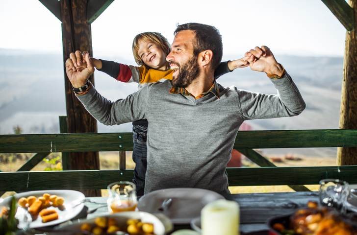 Cheerful father and son having fun during their meal on a terrace.