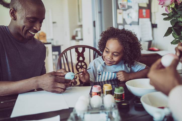 Father and boy colouring Easter egg together